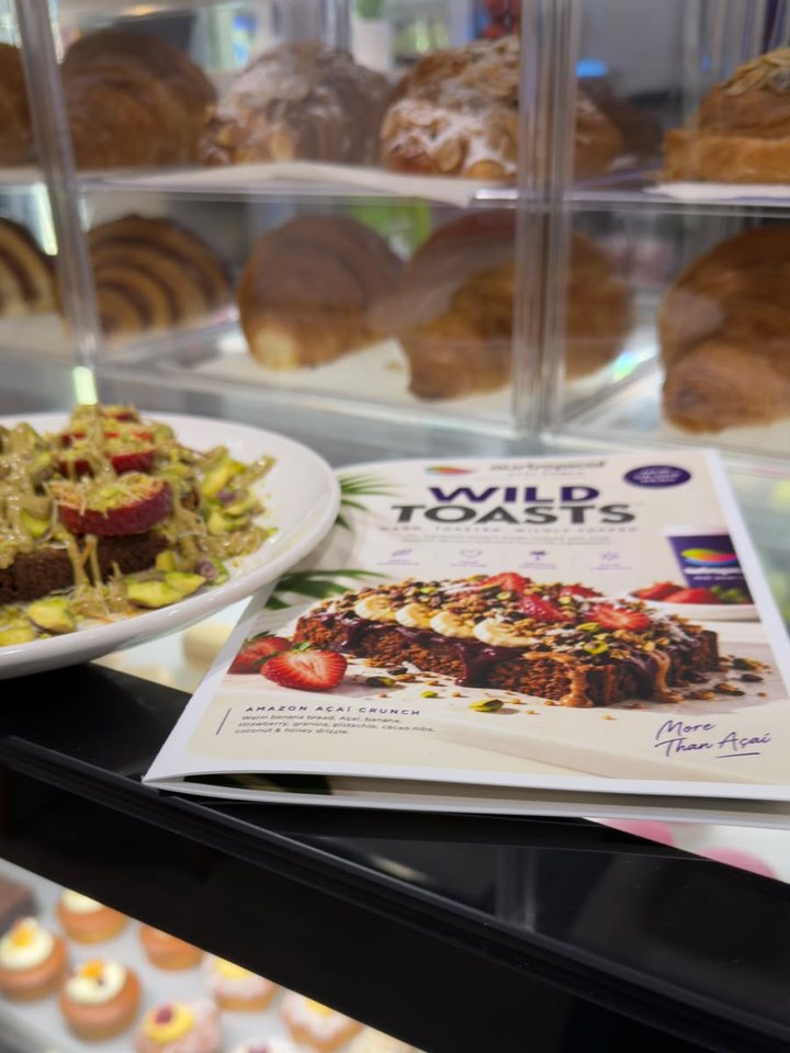 The café cabinet: pastries above, small cakes below, and a plate on the counter beside the menu.