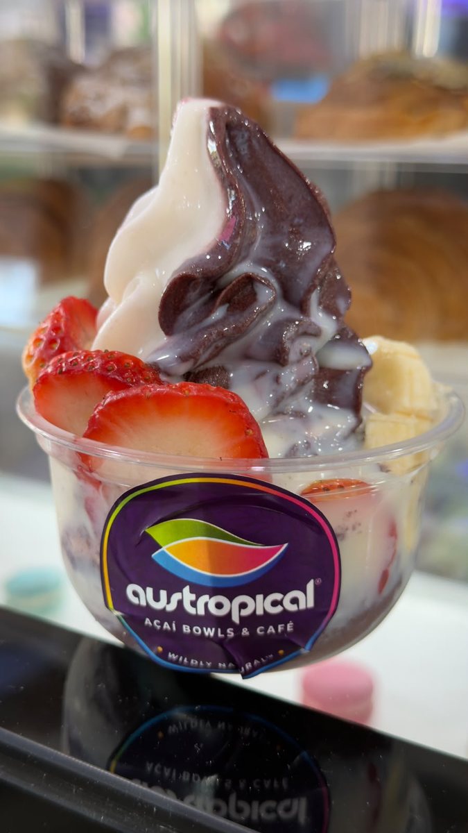 An açaí and vanilla soft-serve swirl with strawberries in a clear Austropical cup.