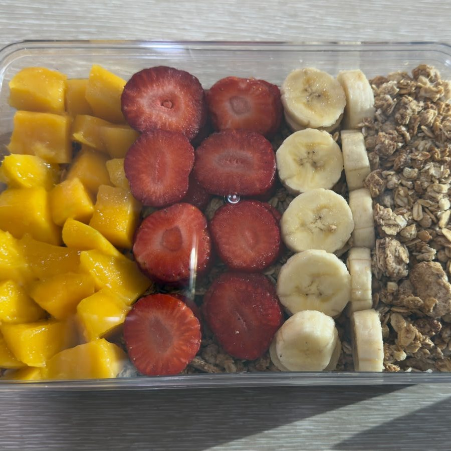 The café's Açaí Party Box from above: rows of mango, strawberry, banana and granola in a clear box.