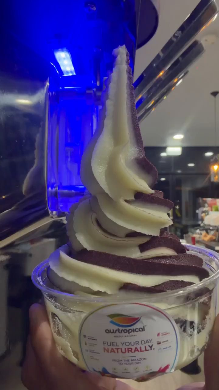 An açaí and vanilla soft-serve swirl built up a clear cup under the machine.