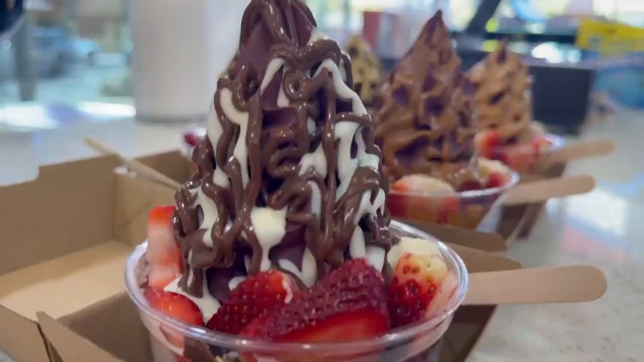A row of açaí soft-serve bowls in takeaway trays on the café counter.