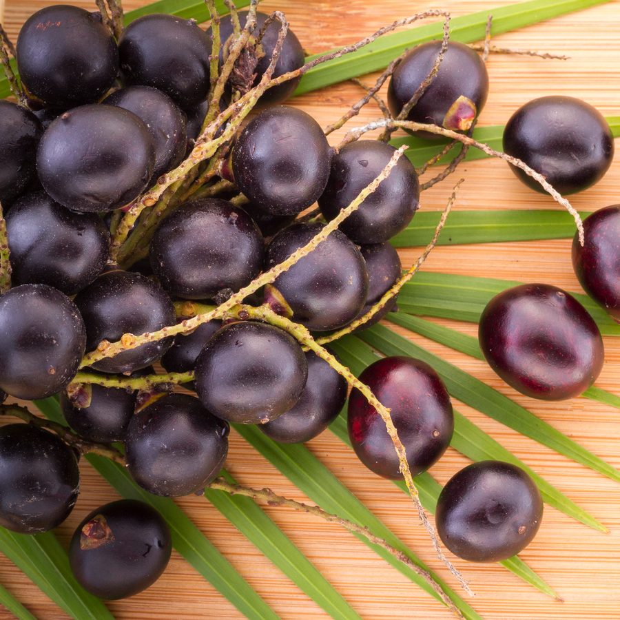 Açaí berries on their stems, on a palm frond